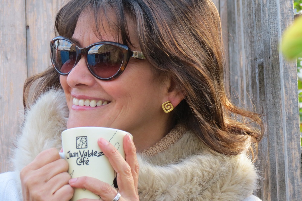 Claudia Gonzalez-Gard Drinking a Juan Valdez coffee and wearing AMAYA Eterno earrings
